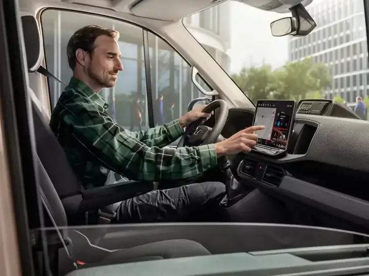 Driver at the wheel of a modern van using the touchscreen